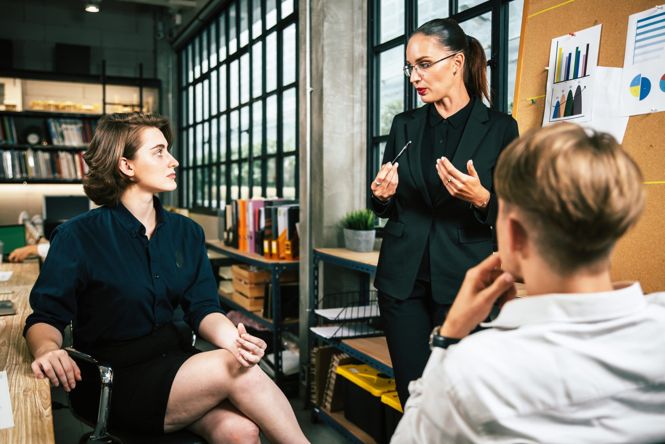 Three colleagues engage in a vibrant business meeting in a modern office setting.